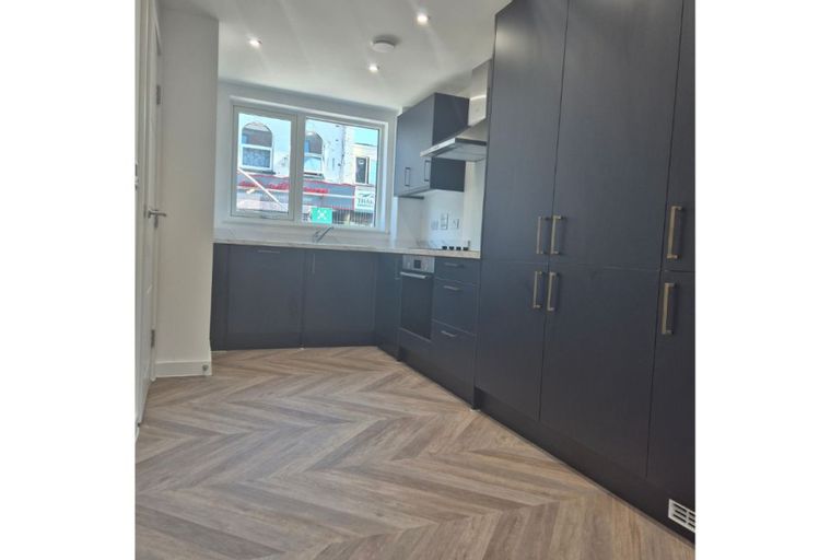 A modern kitchen with dark cabinets, a herringbone floor, and a window.