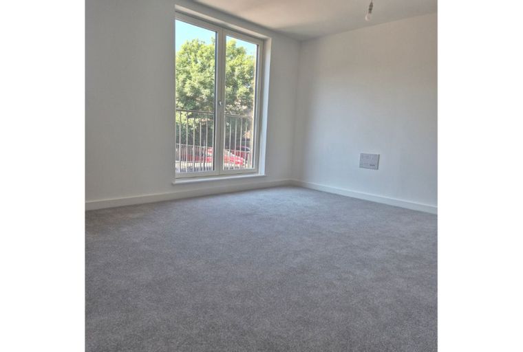 A room with grey carpet and a large window.