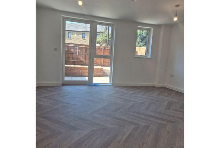 A living room with a herringbone floor and glass doors leading outside.