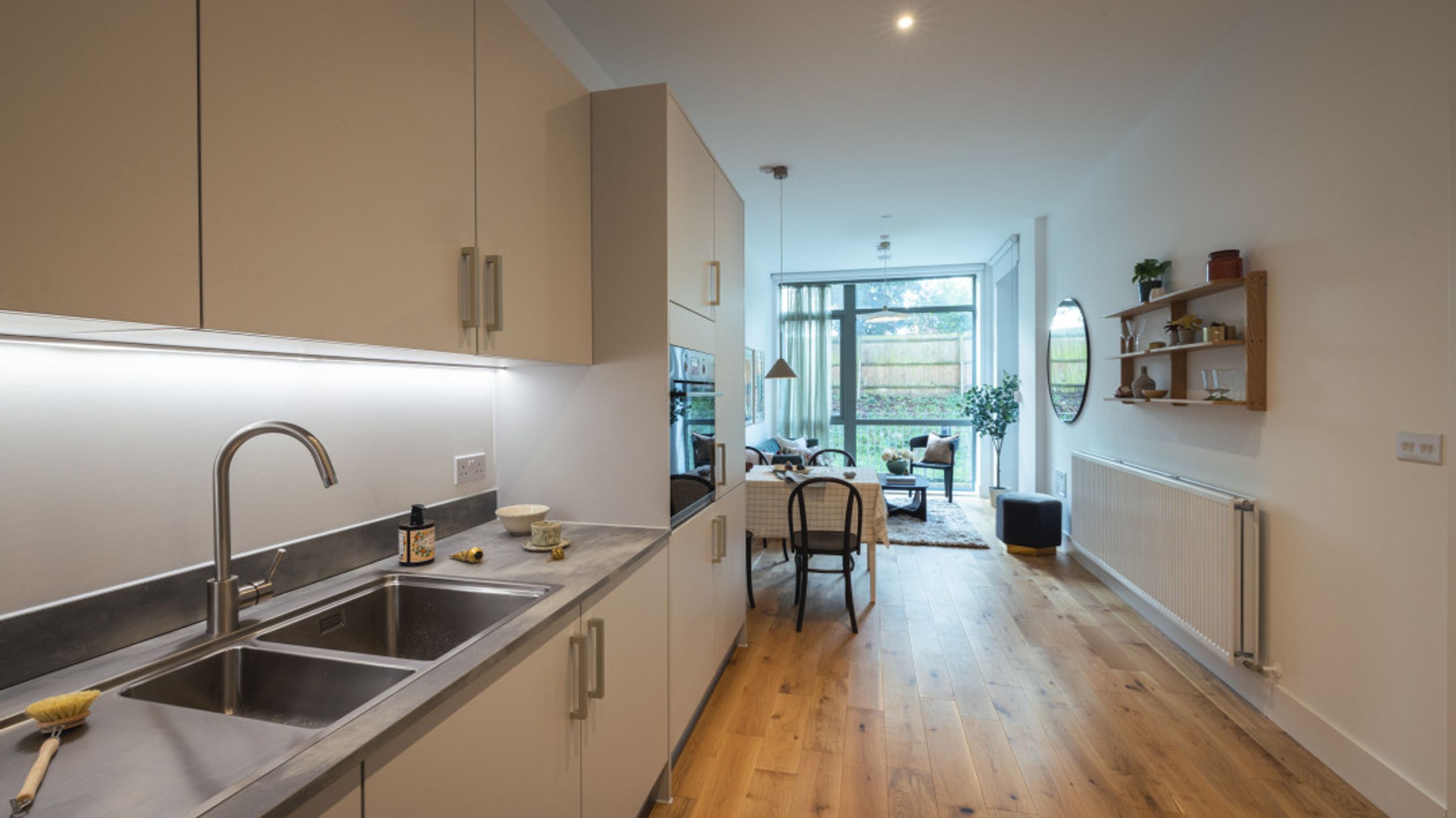 A modern kitchen and living area with a sink, dining table, and large windows.