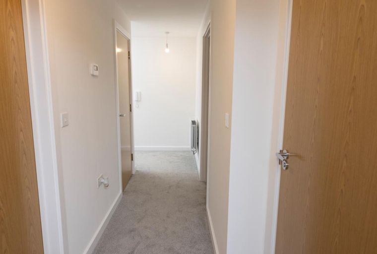 A hallway with wooden doors and grey carpet.