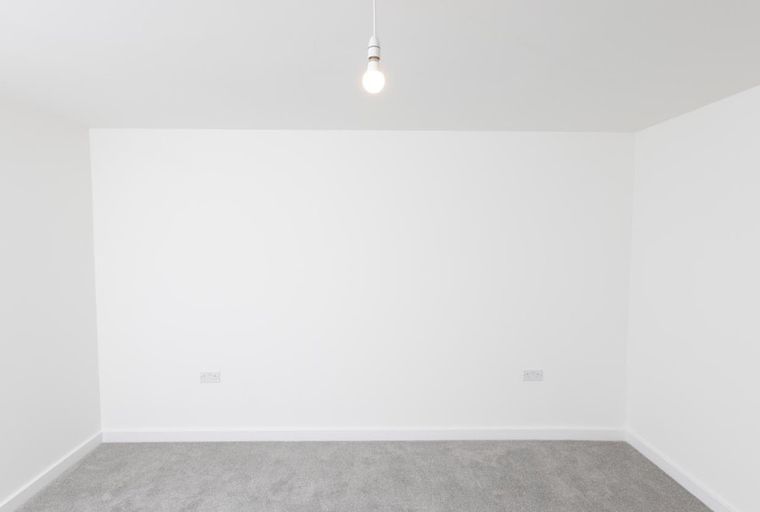 A room with white walls, a grey carpet, and a light fixture.