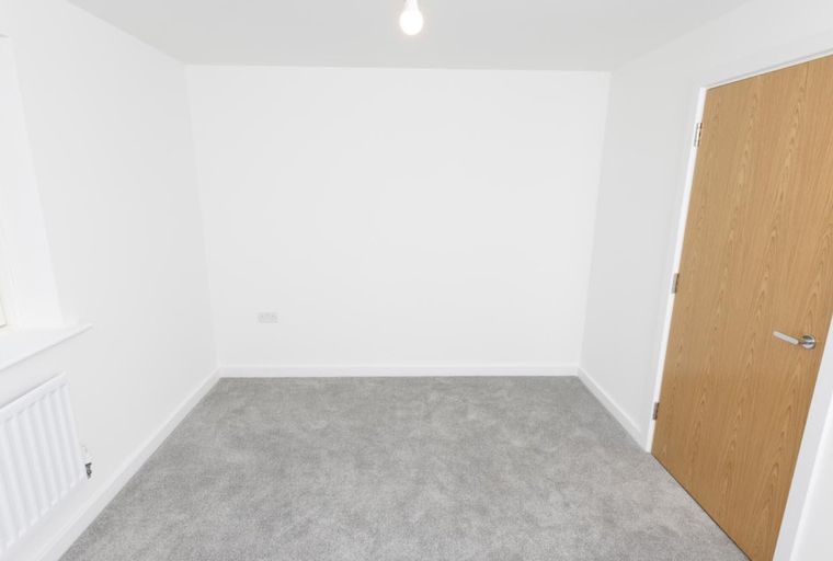 A room with a window, radiator, and a wooden door.