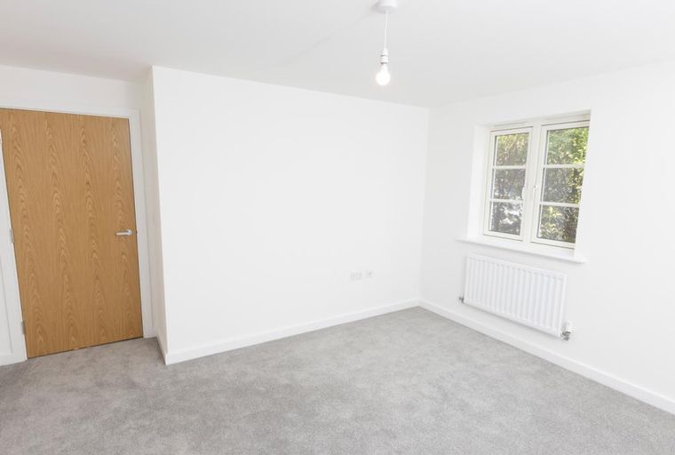 A room with a wooden door, a window, and a radiator.