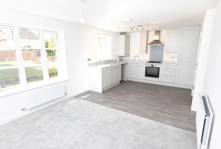 A kitchen and living area with large windows and a radiator.