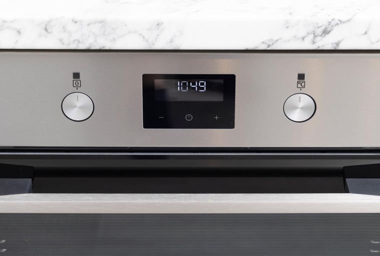 A stainless steel oven with a digital display showing the time 10:49.