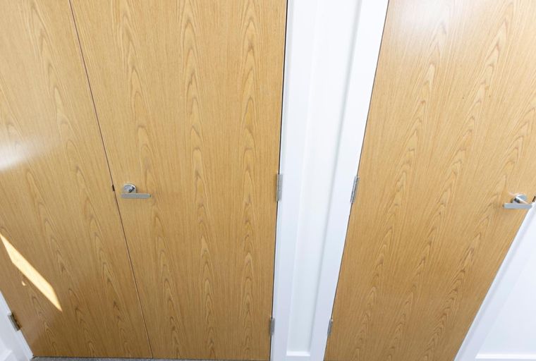 A hallway with two light wood doors and white trim.