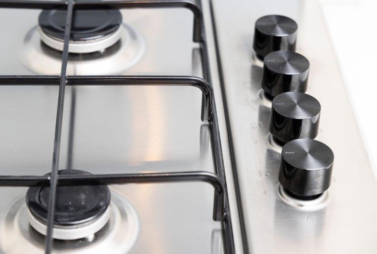 A stainless steel gas stovetop with four burners and black control knobs.