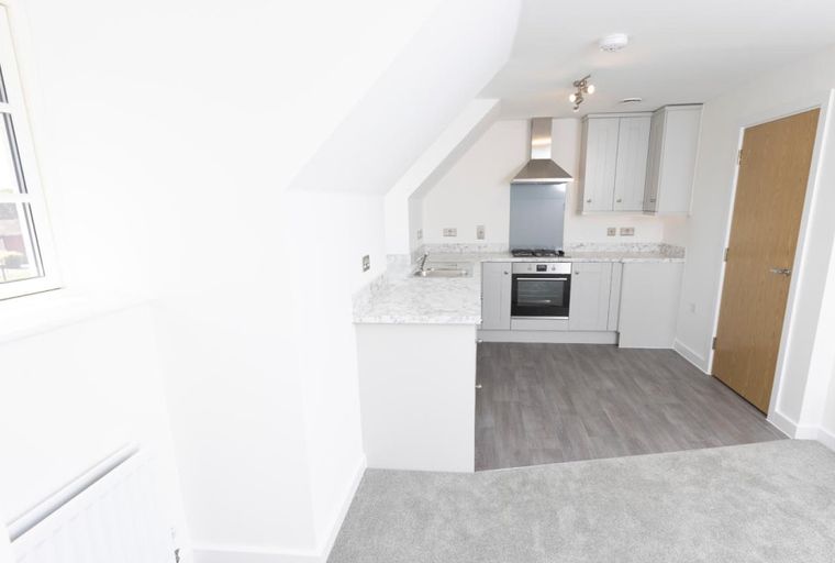 A kitchen area with a sink, oven, and cabinets next to a wooden door.