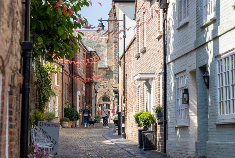 A cobblestone street lined with brick buildings and red bunting.