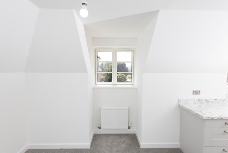 A room with a window, radiator, and kitchen counter.