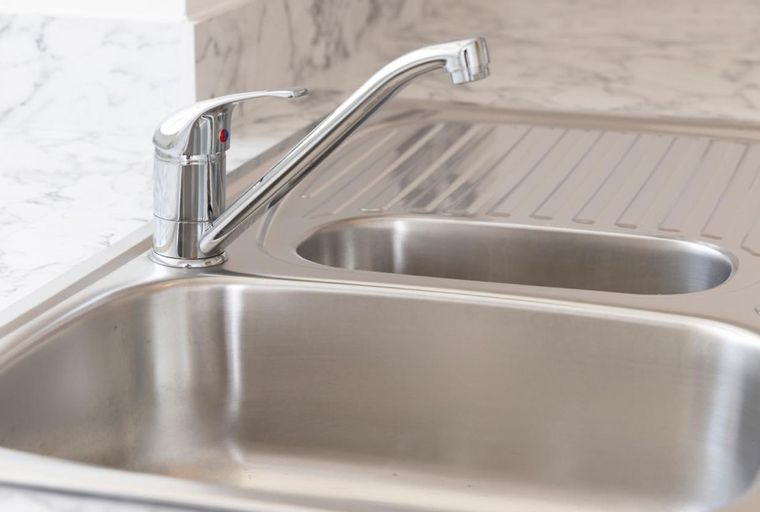 A double basin stainless steel sink with a chrome faucet and a marble countertop.