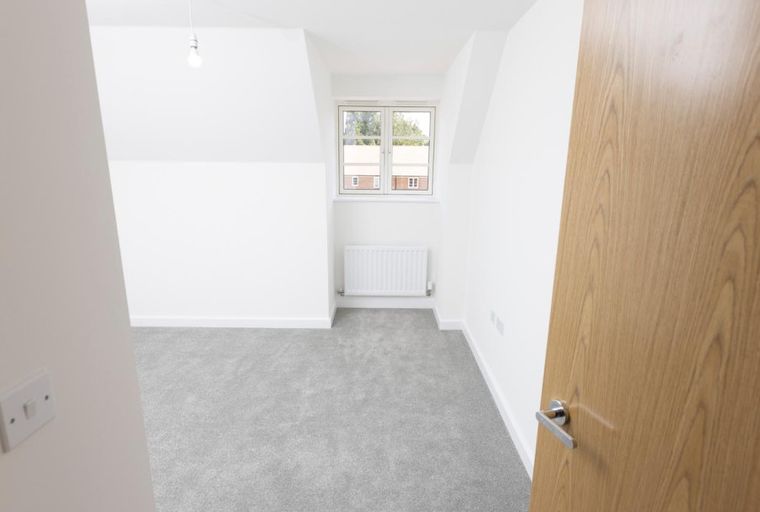 A room with a window, radiator, and a wooden door.