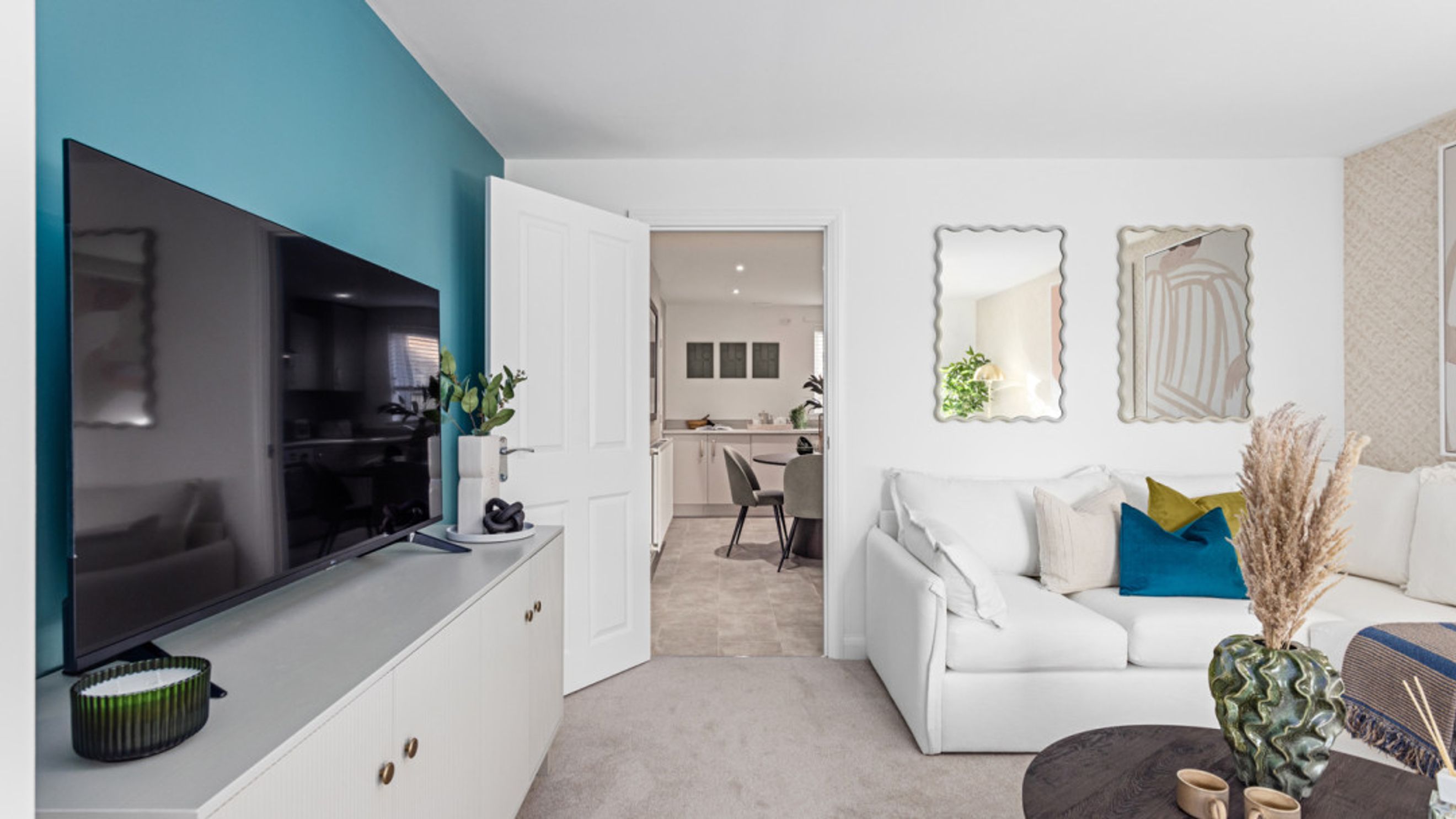 A living room with a TV, sofa, and an open doorway to a kitchen.