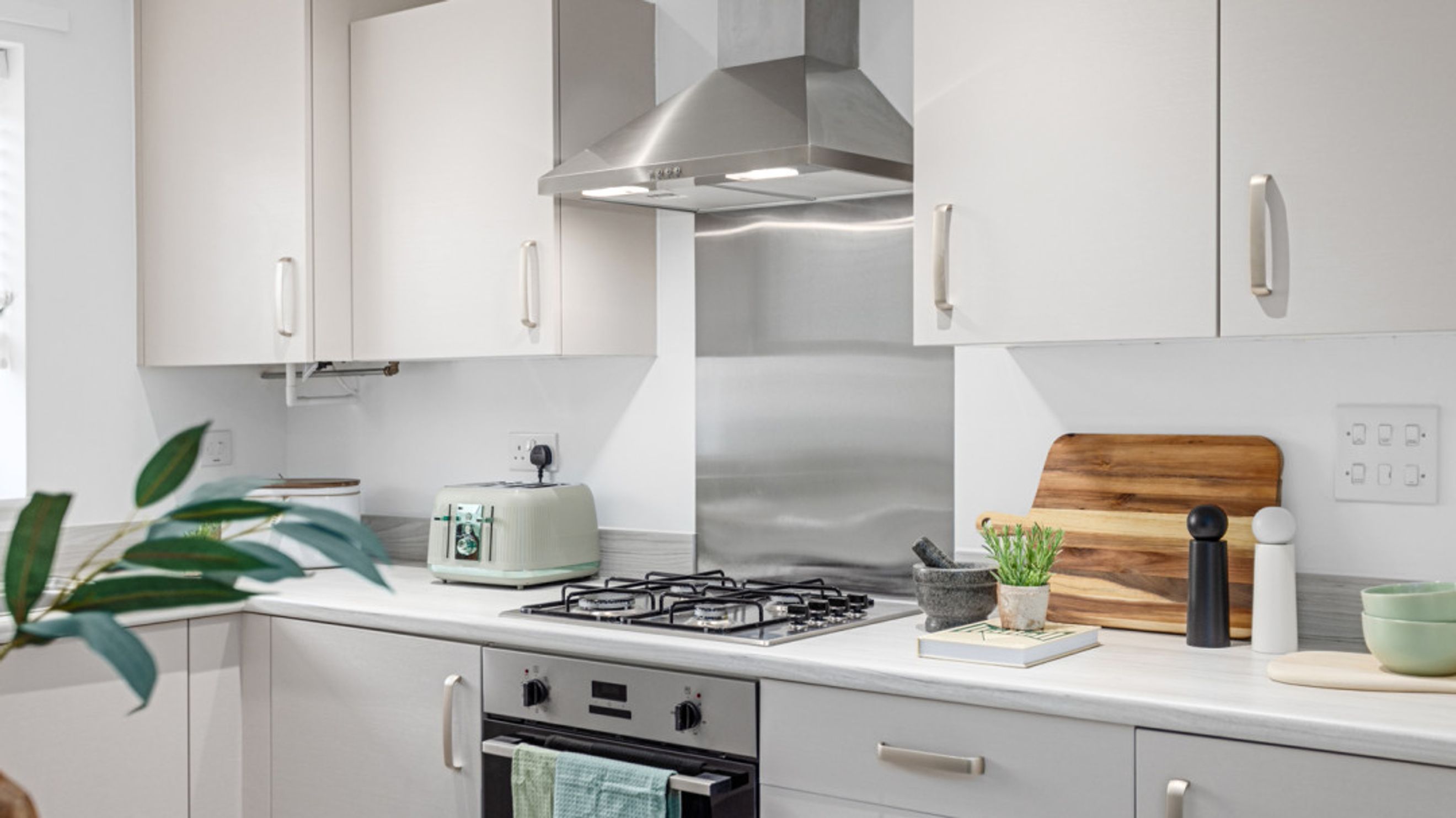 A kitchen with white cabinets, a gas stovetop, and a stainless steel range hood.