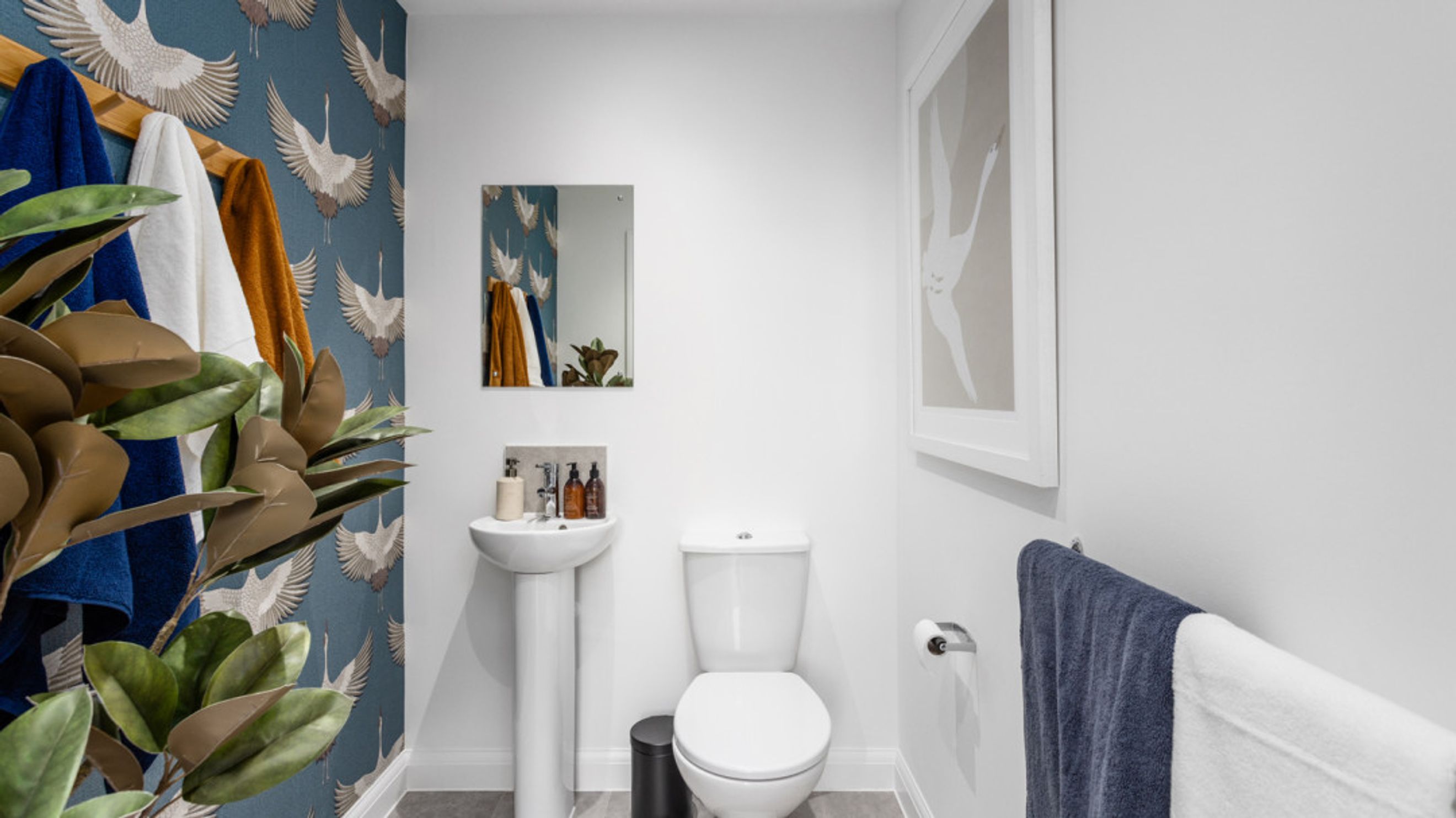 A bathroom with a toilet, sink, mirror, and towels.
