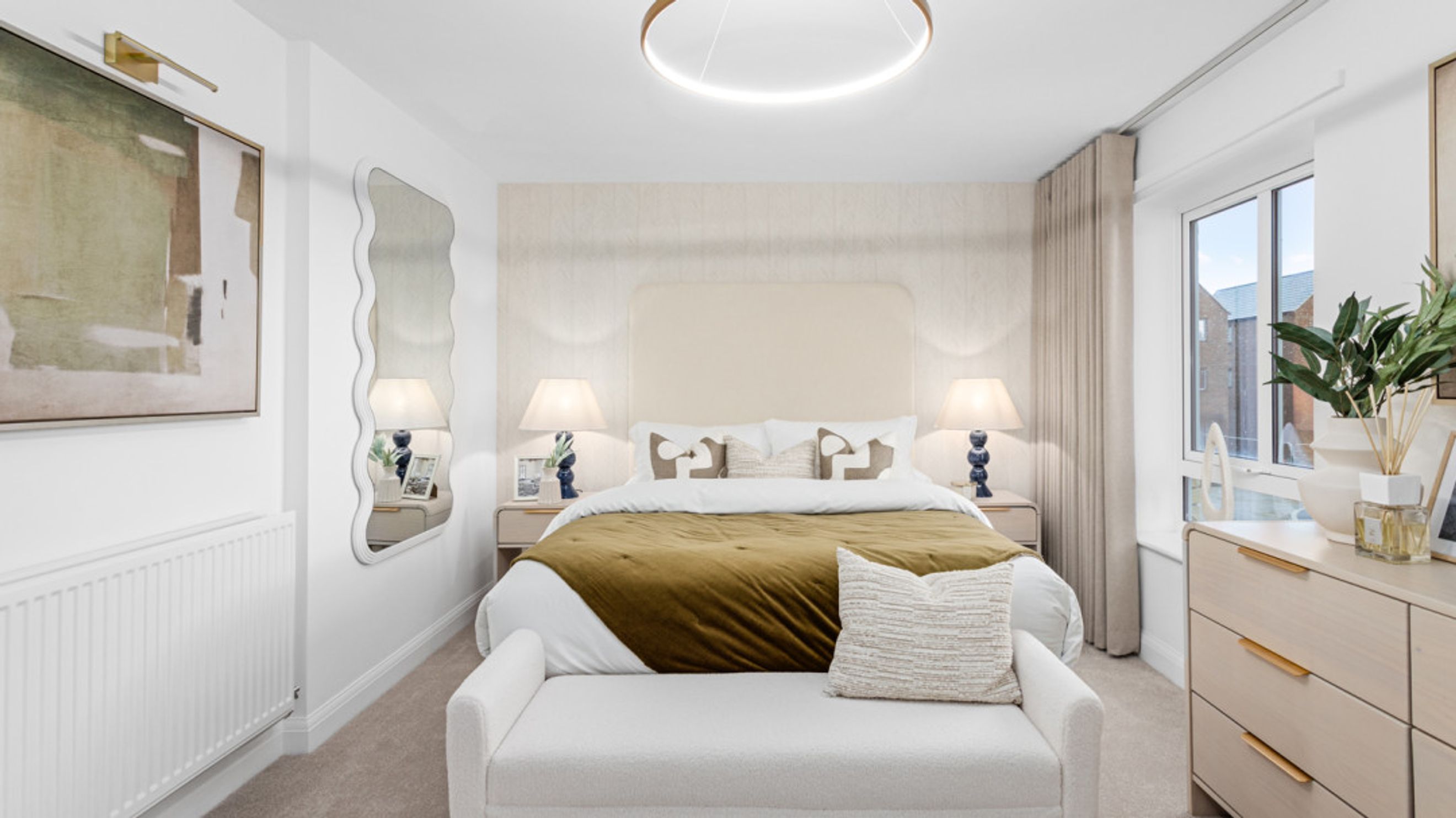 A bedroom with a bed, bedside tables, lamps, and a mirror.