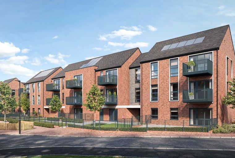 A row of modern red brick apartment buildings with balconies and solar panels under a blue sky.