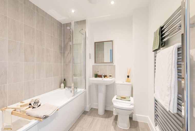 A bathroom with a bathtub, sink, toilet, and heated towel rail.