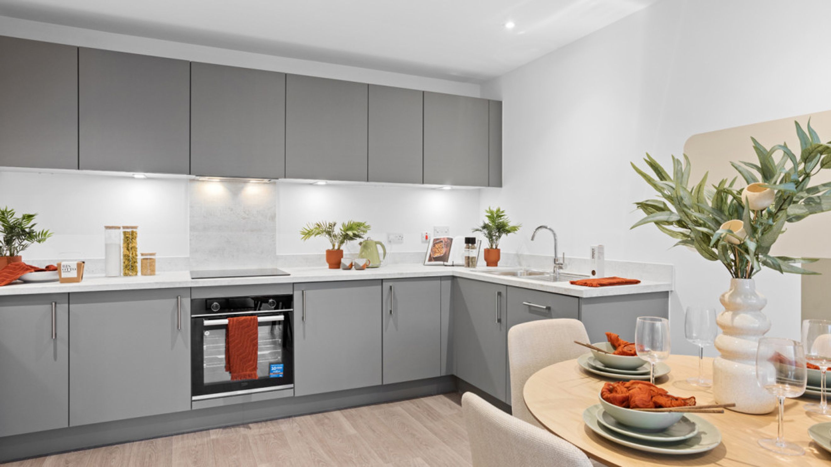 A modern kitchen and dining area with grey cabinets, an oven, and a round dining table.