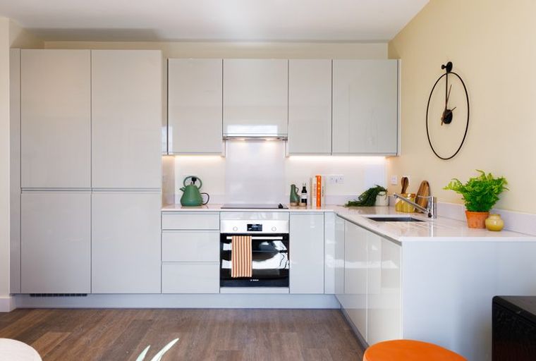 A modern kitchen with white cabinets, an oven, and a sink.