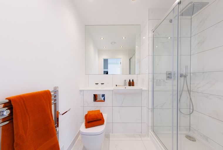 A bathroom with a toilet, sink, and a glass-enclosed shower.