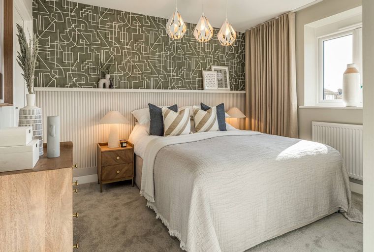 A bedroom with a bed, bedside tables, lamps, and patterned wallpaper.