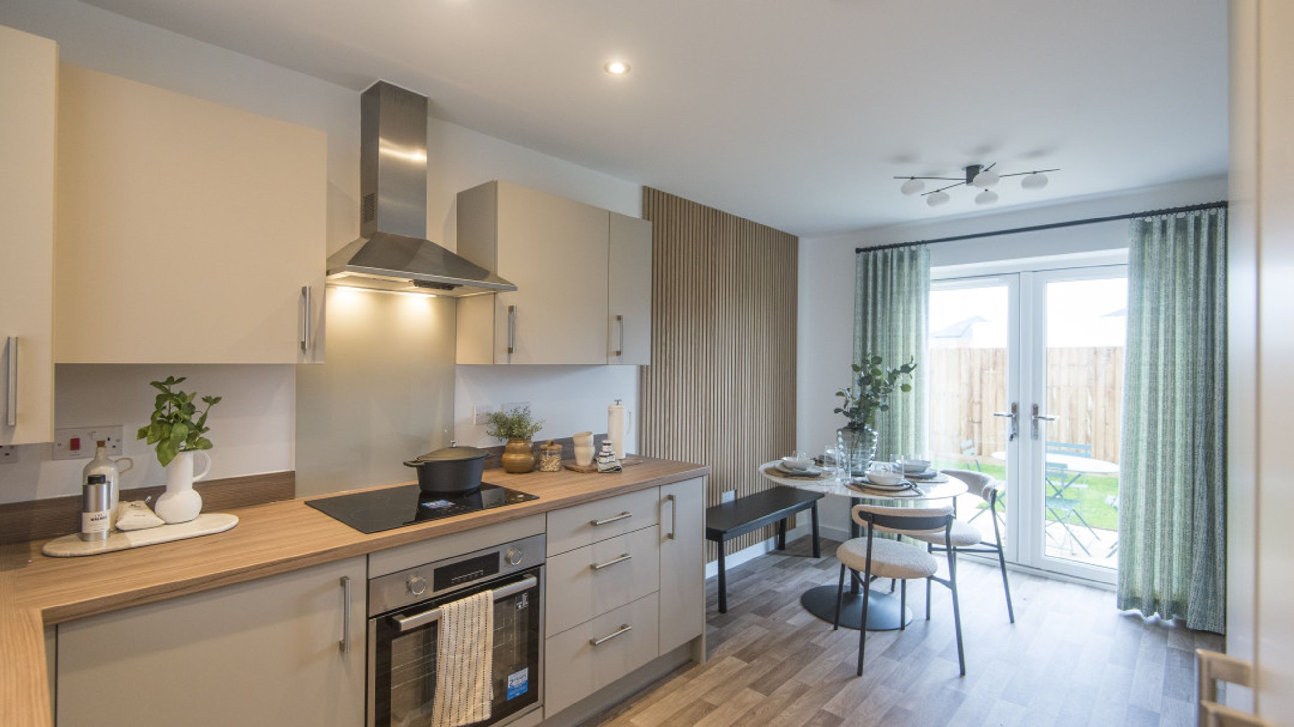 A kitchen and dining area with a stove, cabinets, a round table, and chairs.