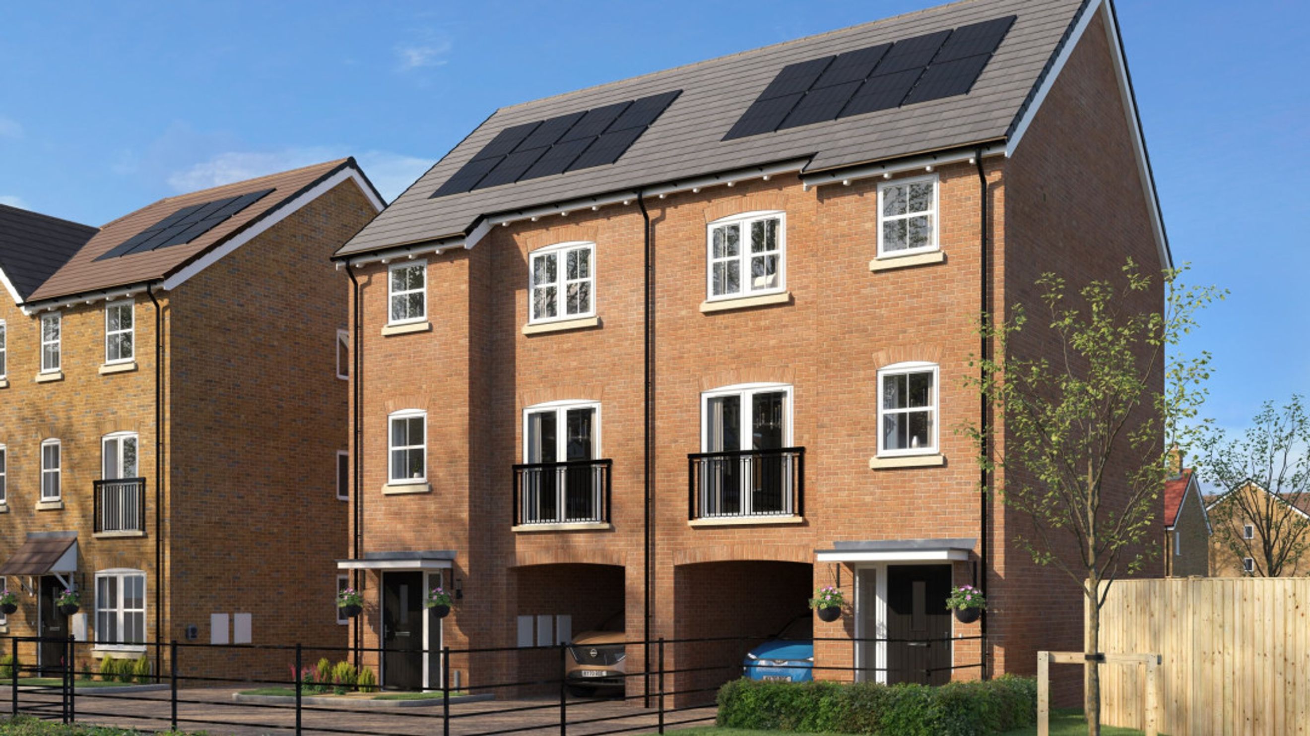 A row of modern brick townhouses with solar panels on the roof, balconies, and covered parking.