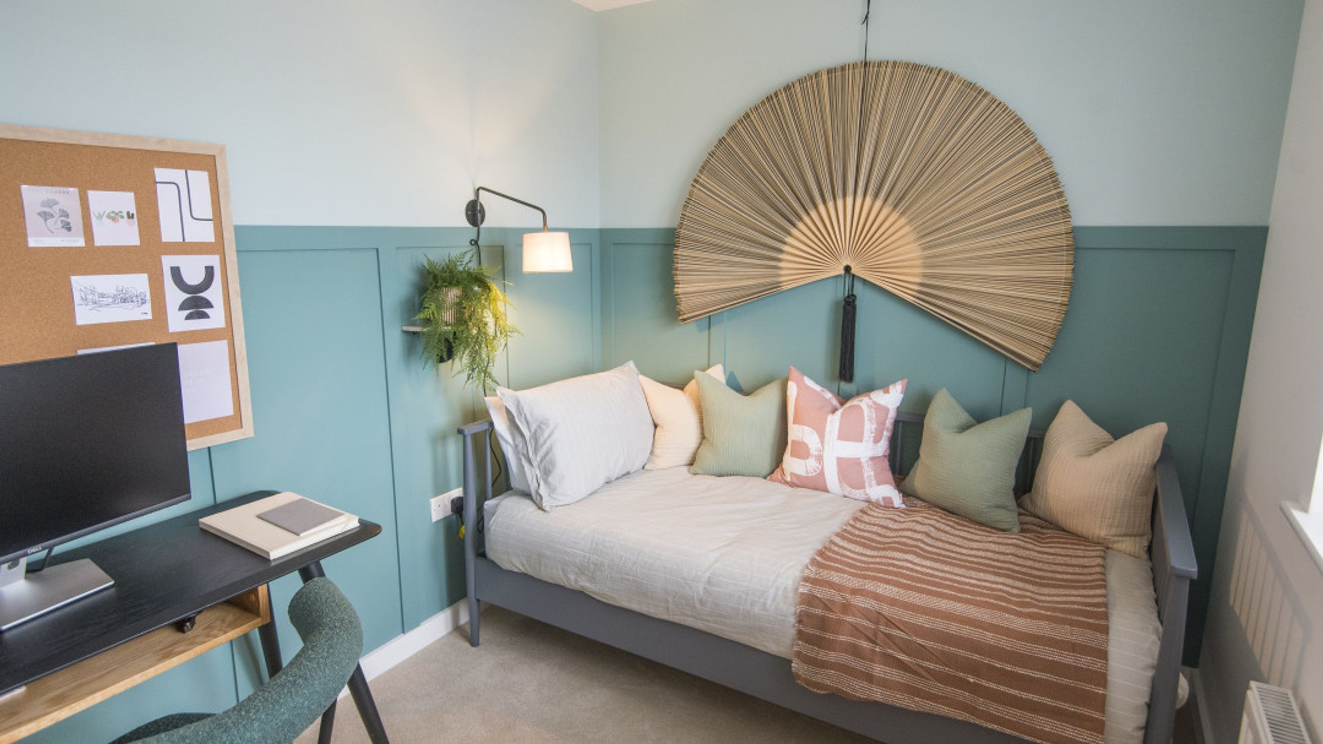 A bedroom with a daybed, desk, and wall art.