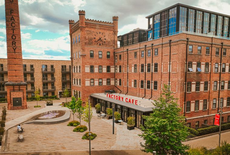 A brick factory building with a clock tower and a cafe.