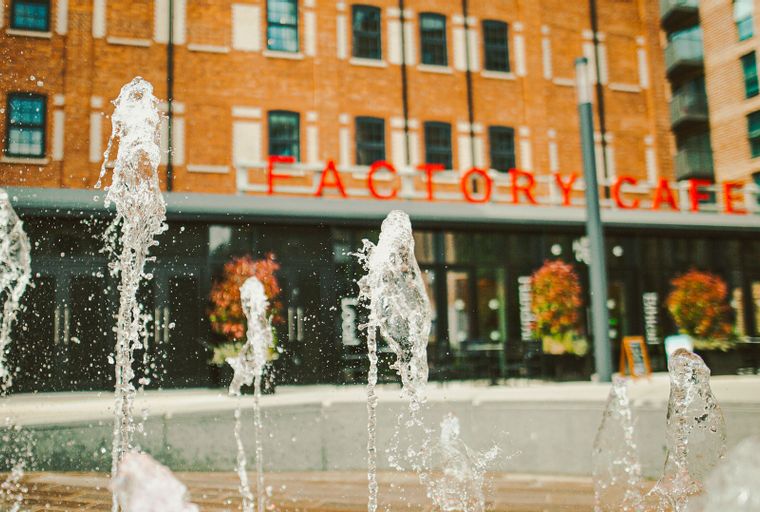 A fountain in front of a building with the words 'FACTORY CAFE' on it.