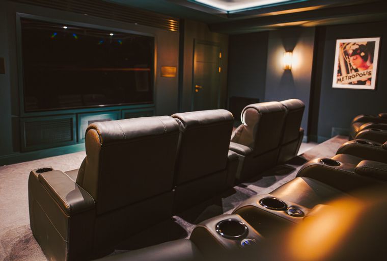 A home theater with rows of leather recliners facing a large screen.
