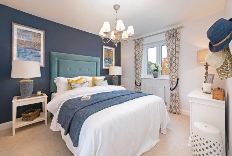 A bedroom with a bed, nightstands, a chandelier, and a window with curtains.