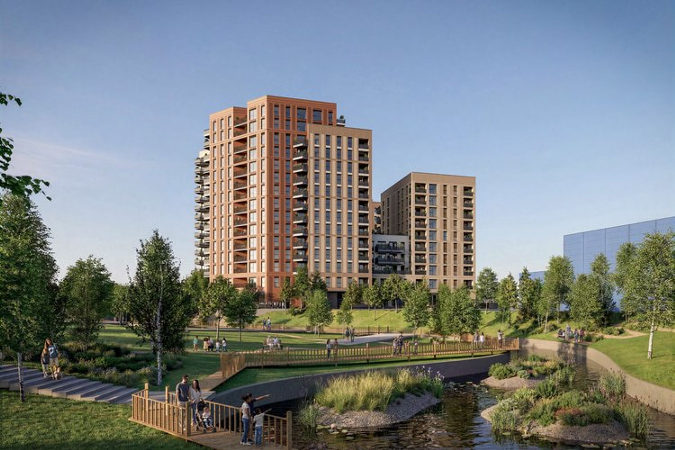 A modern apartment complex with balconies overlooking a park and a stream.