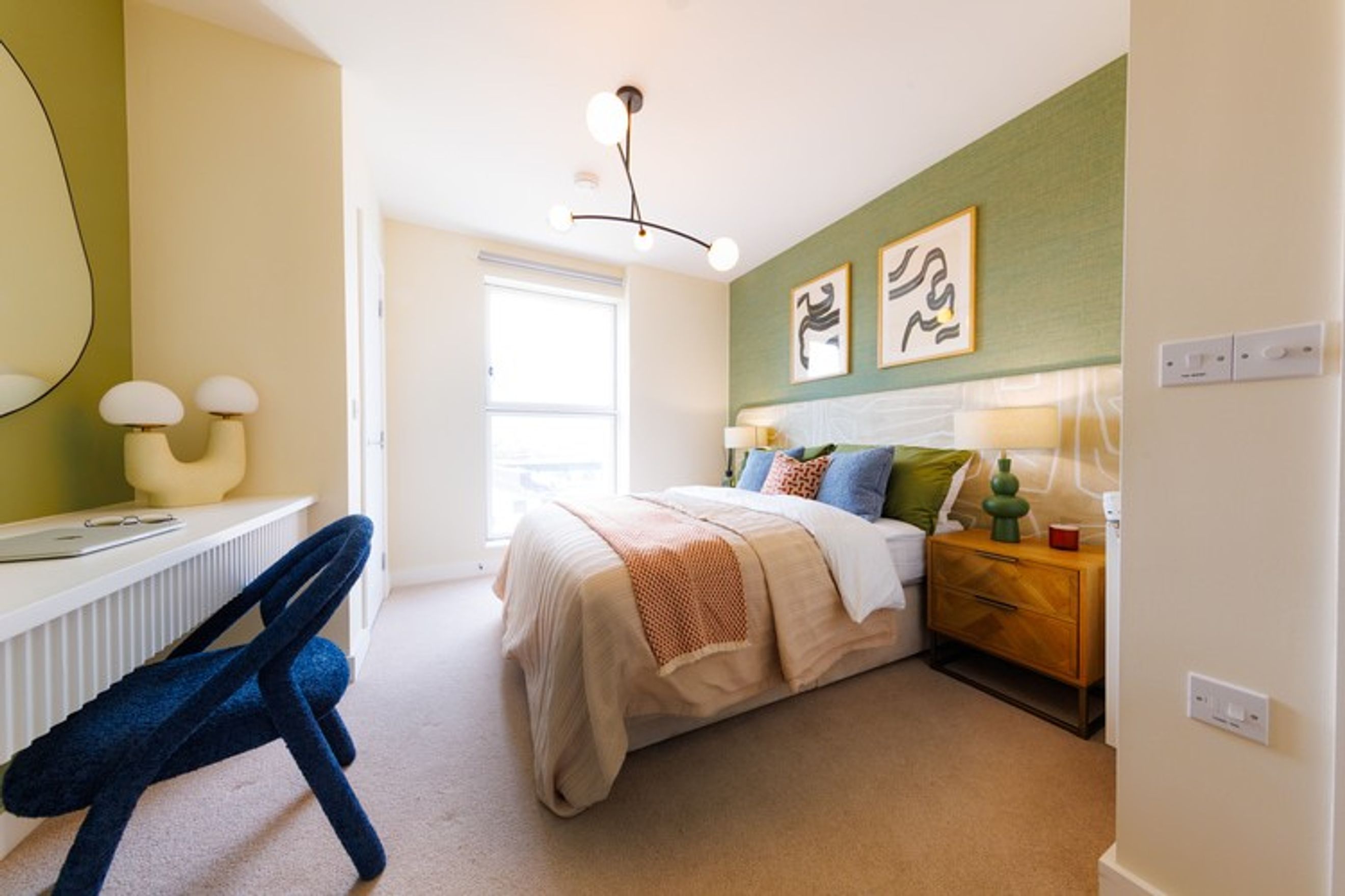 A bedroom with a bed, bedside table, and a desk.