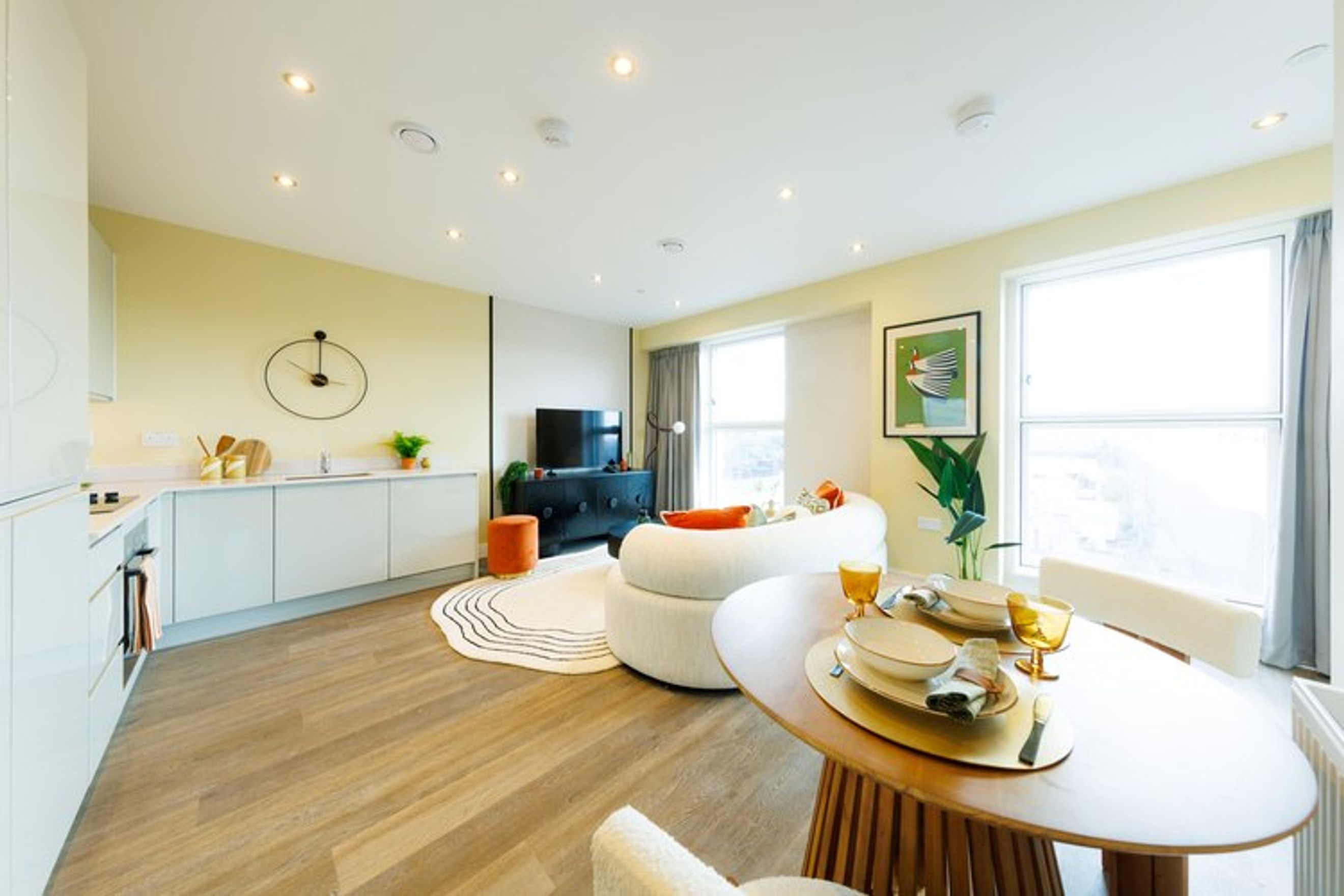 A dining area and living room with a sofa, dining table, and kitchen counter.