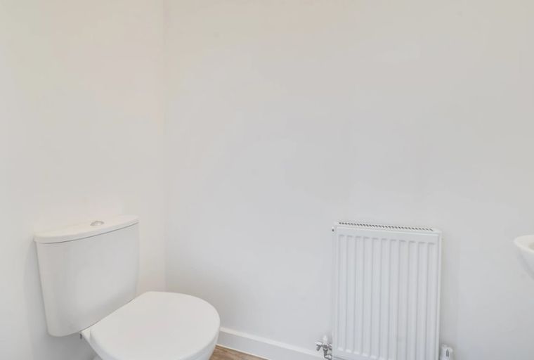 A toilet, a radiator, and a sink in a white bathroom.