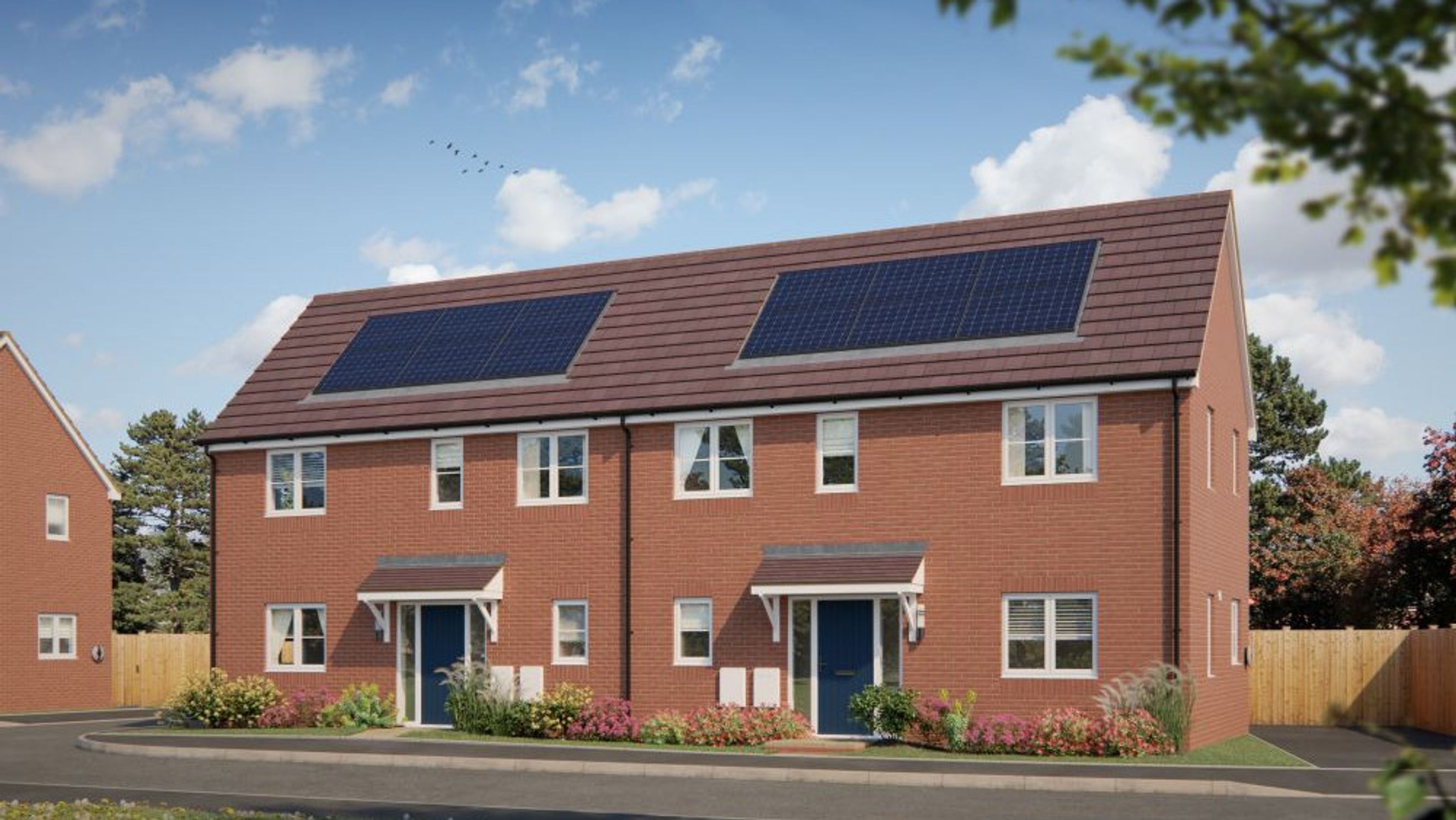 A row of red brick townhouses with solar panels on the roof, blue front doors, and gardens.