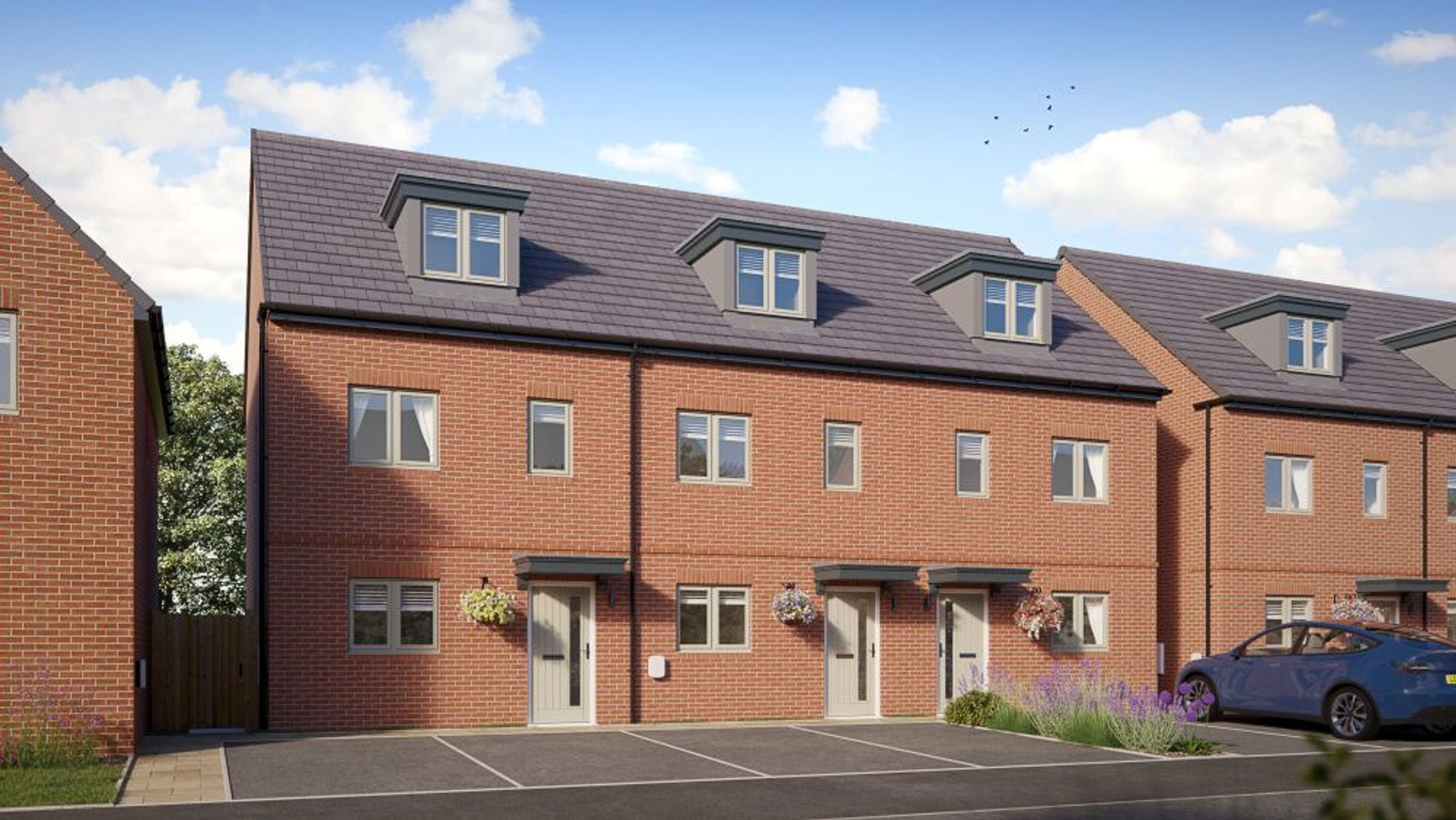A row of red brick townhouses with dormer windows and front doors.