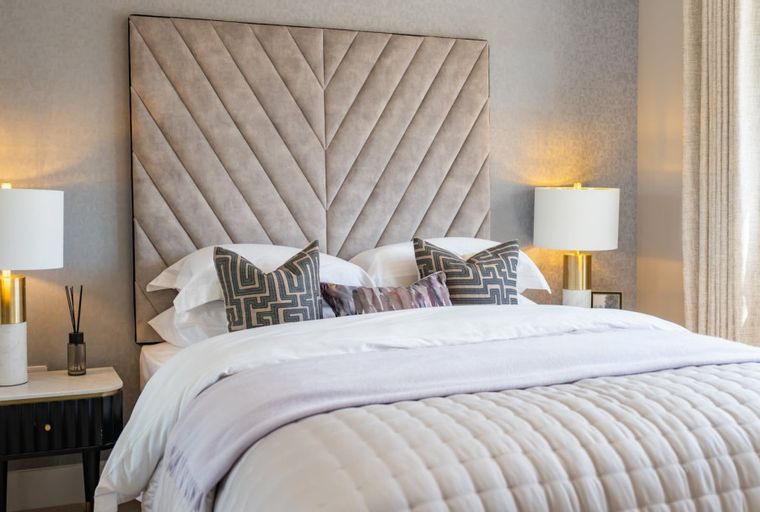 A bedroom with a bed, pillows, and bedside lamps.