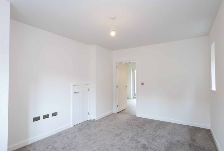 A room with white walls, grey carpet, and multiple doors.