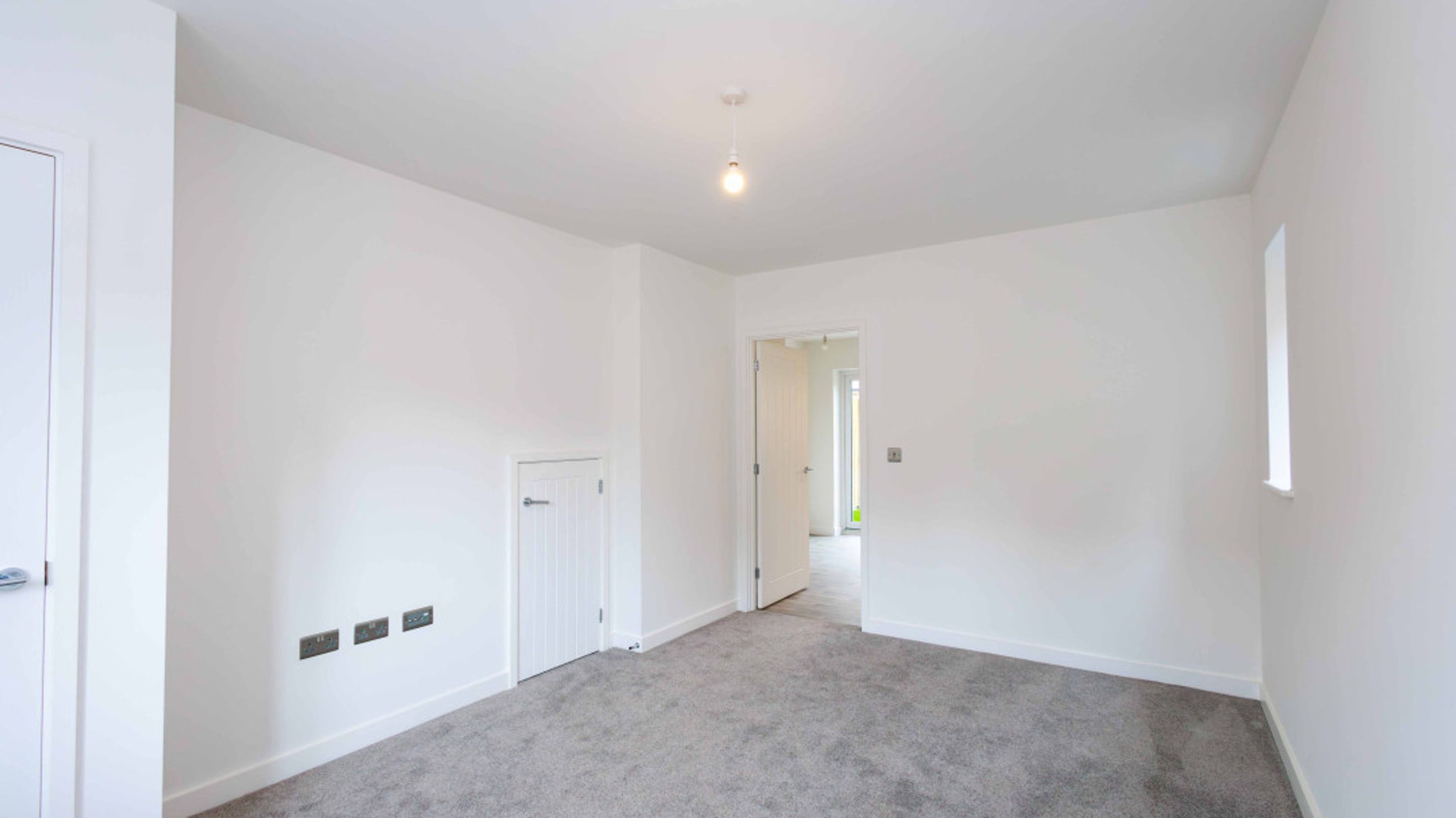 A room with white walls, grey carpet, and multiple doors.