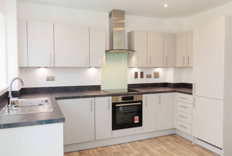 A modern kitchen with white cabinets, a dark countertop, and stainless steel appliances.