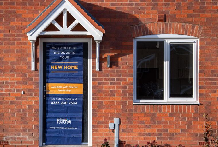 A front door with a sign advertising a new home available with shared ownership.