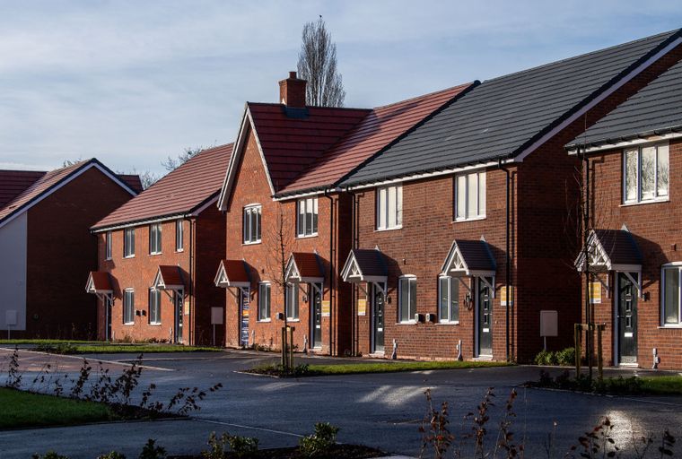 A row of new brick townhouses with pitched roofs and awnings over the doors.