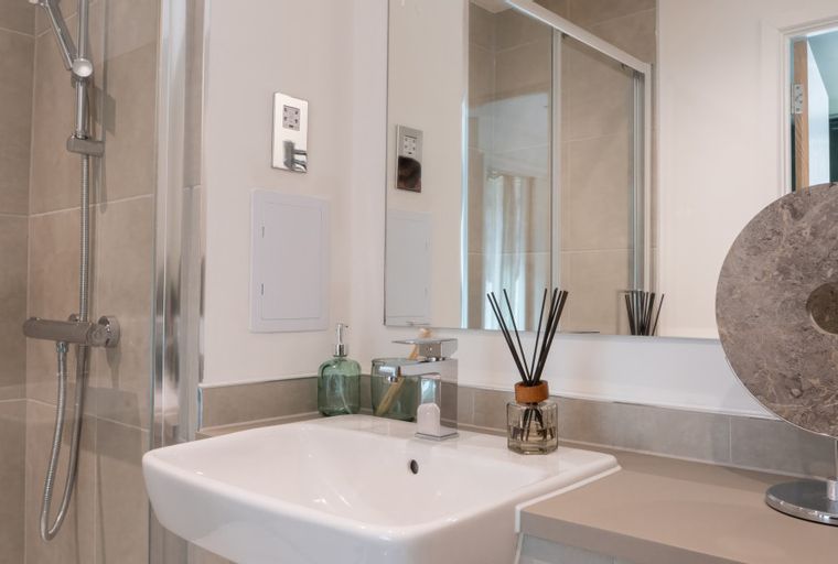 A bathroom with a sink, shower, and mirror.