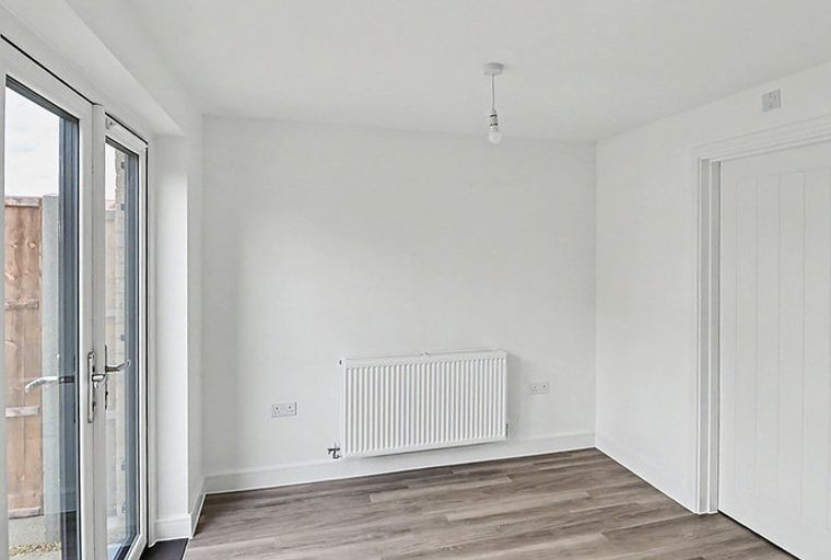 A room with double doors, a radiator, and a white door.