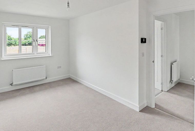 A bedroom with a window and a radiator.