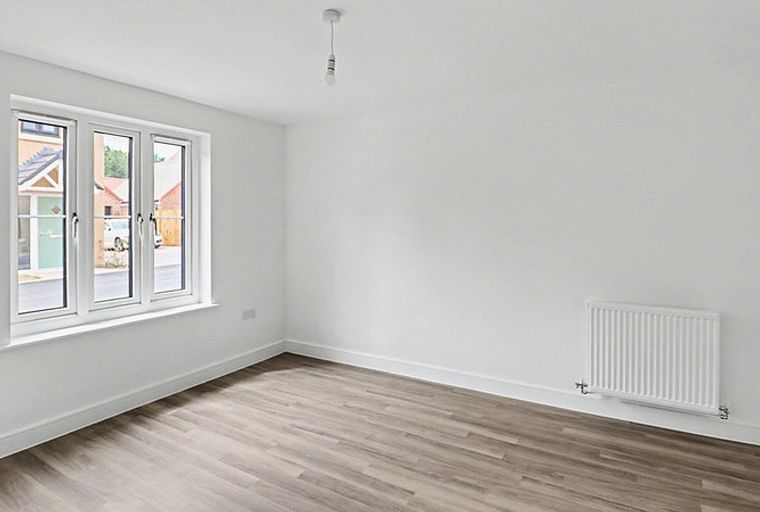 A room with a window, a radiator, and a light fixture.